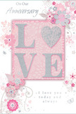 This anniversary card presents itself with a quiet, luminous beauty, reminiscent of a soft pastel bouquet arranged by hand in a Cowley shop and delivered just in time for a special evening. The central feature is the word LOVE, set in generously sized capital letters that are gently raised from the card, their surfaces kissed with fine glitter. The shimmer is delicate and refined, giving the letters a pearlescent glow when they catch the light. Surrounding this central declaration, a constellation of stylised flowers and flowing foliage winds across the front, drawn in slender, looping lines that mimic the natural curves of stems and tendrils. The blossoms are suggested rather than strictly defined, brushed in tones of blush pink, soft white, and the palest mauve, with subtle silver accents highlighting petals and leaves. The background is an even, comforting pink-light enough to feel airy, yet warm enough to hold the design together, much like the calm warmth of Cowley's quiet streets at dusk. Within this floral tapestry, an anniversary greeting appears in elegant, script-style text, the words nestled among the swirls and leaves as if cradled within a bouquet. The overall mood of the card is gently celebratory rather than loud; it whispers of long-standing love, shared routines, and cherished small moments. The interplay of raised texture, smooth cardstock, and fine illustration invites both touch and reflection, creating a keepsake that feels personal, considered, and perfectly suited to marking another year of life spent side by side in familiar, beloved surroundings.